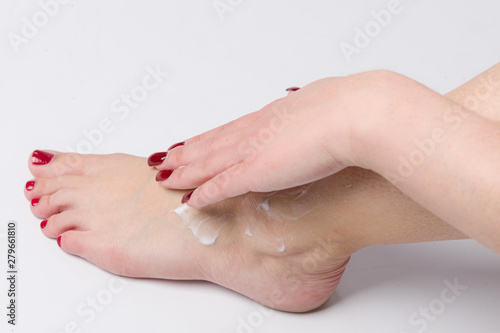 giving own feet a massage with skin cream