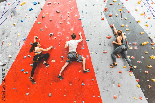 Wspinacz sportowców porusza się po stromej skale, wspinając się na sztucznej ścianie w pomieszczeniu. Sporty ekstremalne i bouldering