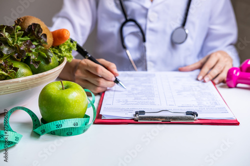 Fotografie Nutritionist with healthy fruit, vegetable and measuring tape working, Right nut