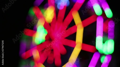 Blurred Ferris Wheel with colorful lighting decoration rotates slowly at night fun fair