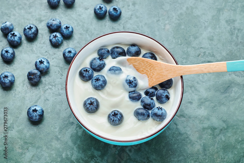 Bowl with yogurt and blueberries on table, top view