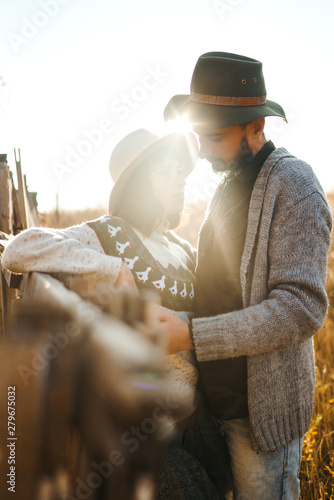 Lovely hipster couple looking at each other. Couple wearing beautiful hats and sweaters. Lifestyle, happy couple of two play on a sunny day in the park. The concept of youth, love and lifestyle. 