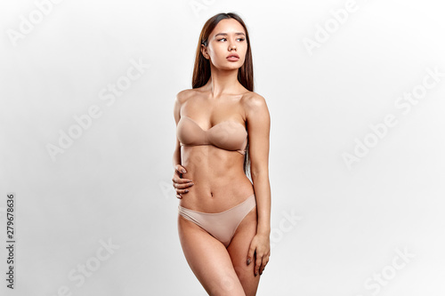confident beautiful woman in sexy beige lingerie posing isolated on a white background. grace and gracefullness