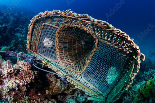 An abandoned underwater fish trap resting on corals on a tropical reef in Asia
