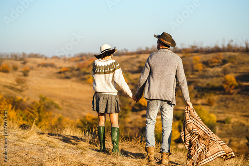 Back view. Lovely hipster couple enjoying each other. Couple wearing beautiful hats and sweaters. Lifestyle, happy couple of two play on a sunny day in the park. 
