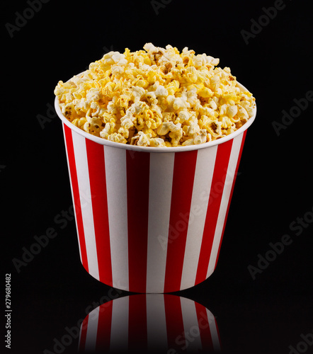Paper striped bucket with popcorn isolated on black background