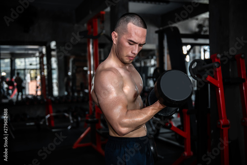 Portrait of asian man big muscle at the gym Thailand people Workout for good healthy Body weight training Fitness at the gym concept Prank to abdominal muscles Lift up dumpbell