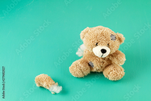 Toy teddy bear with teared away paw