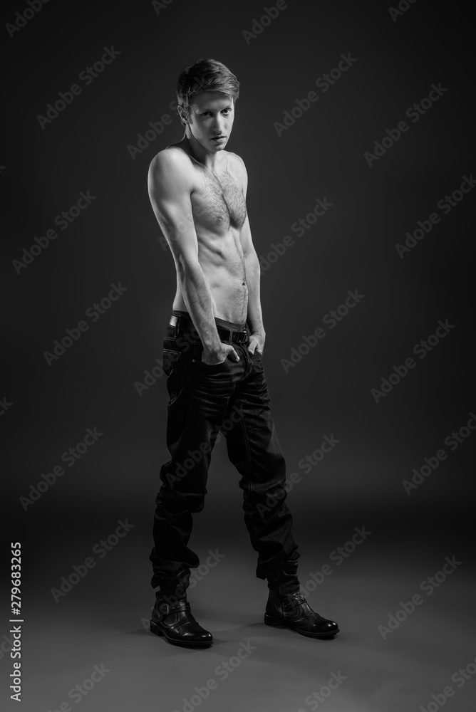 Full length portrait of a sexy young man in jeans and shirtless posing at studio.