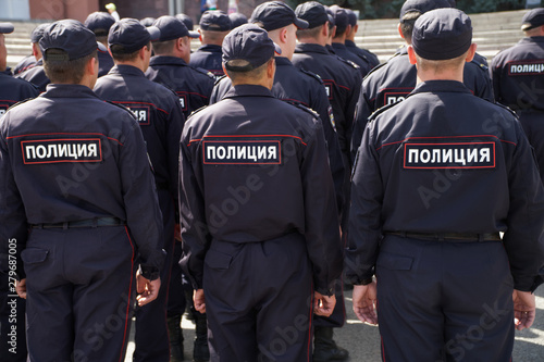 A squad of Russian police officers is preparing to work at a meeting. View from the back