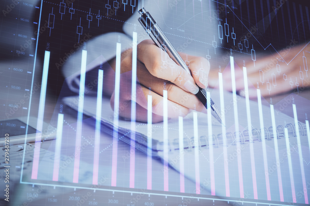 A woman hands writing information about stock market in notepad. Forex chart holograms in front. Concept of research. Multi exposure A woman hands writing information about stock market in notepad. Forex chart holograms in front. Concept of research. Multi exposure