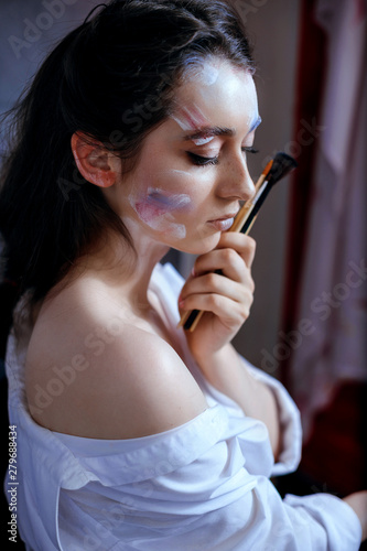 Creative fashion beauty portrait of a beautiful young woman with a brush for cosmetics
