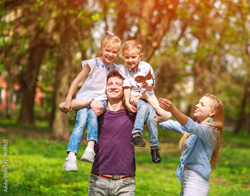 Portrait of family having fun in flowering city park on bright sunny day happily spending their leisure time together outdoors