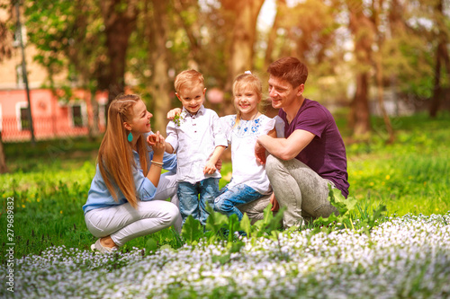 Portrait of family having fun in flowering city park on bright sunny day happily spending their leisure time together outdoors