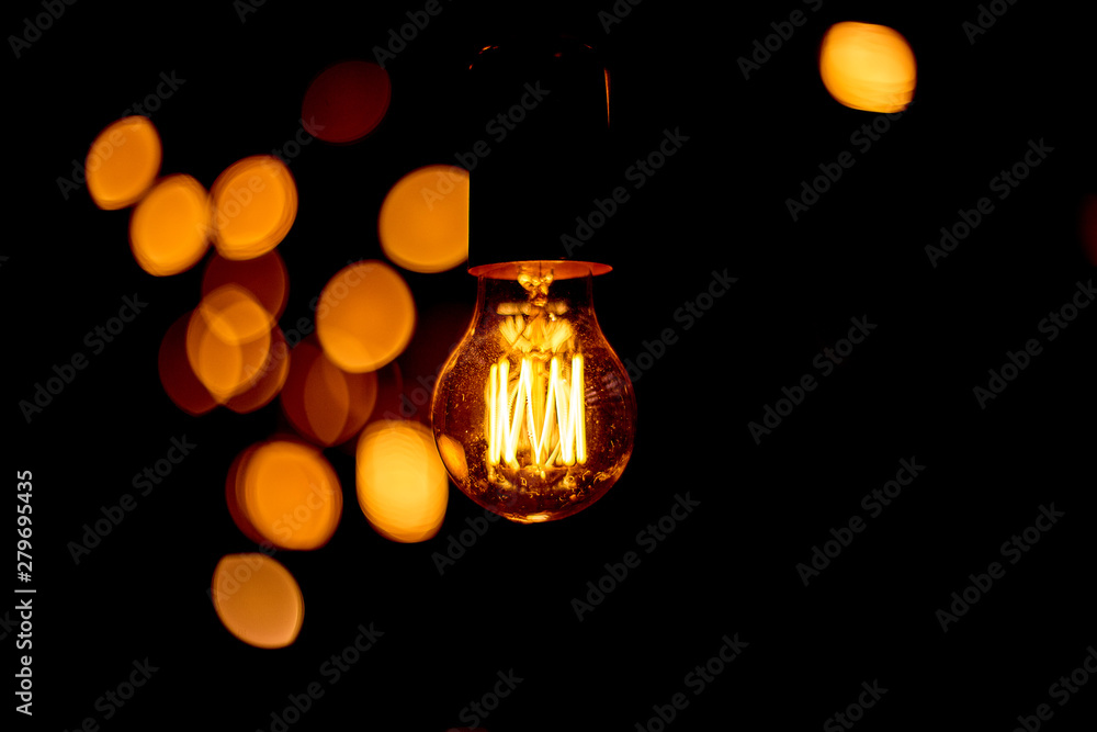 Yellow retro incandescent bulbs hang in the evening at a party. Light bulbs hanging on a wooden bridge at night.