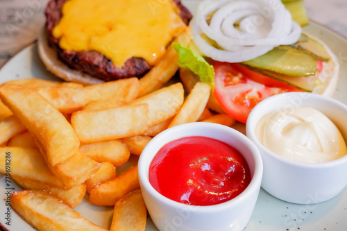 still life with fast food hamburger menu, french fries and ketchup.Junk food. Fast carbohydrates not good for health, heart.Restaurant serving of burger with fries. plate with traditional american