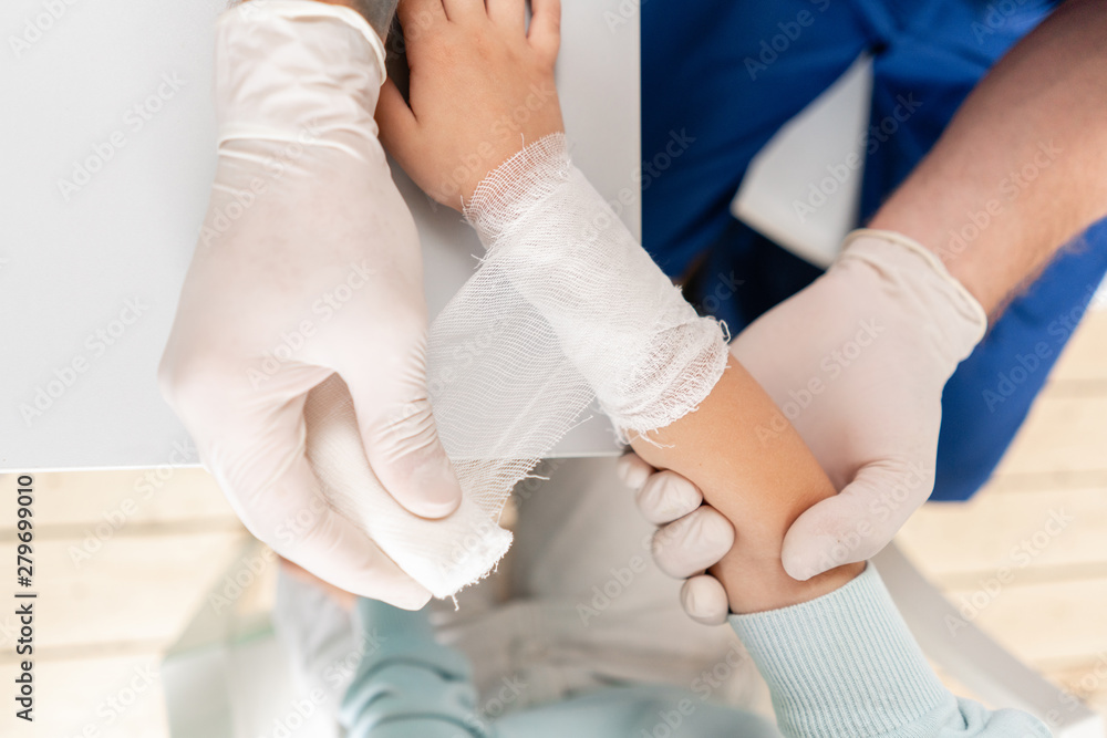 Doctor bandaged a boy hand with trauma in his arm. Elastic bandaged around his hand Doctor bandaged a boy hand with trauma in his arm. Elastic bandaged around his hand