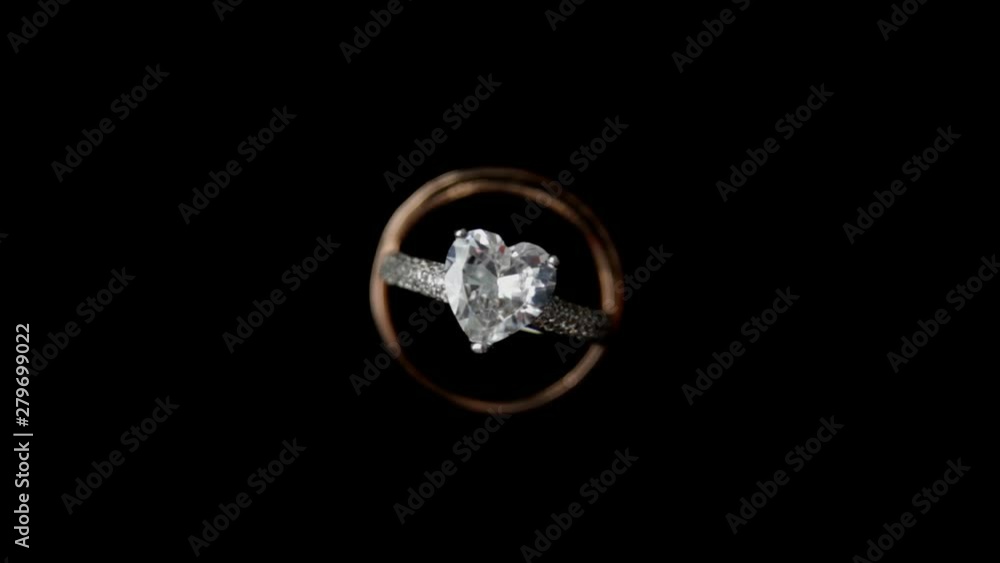 Camera circulating around heart shape wedding ring on dark background close up Camera circulating around heart shape wedding ring on dark background close up