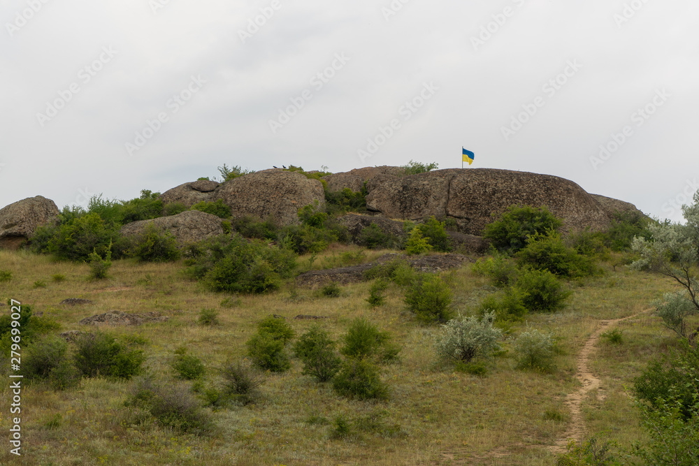 Large granite canyon. Village Aktove. Ukraine. Beautiful stone landscape. Ukrainian flag on top of a cliff.