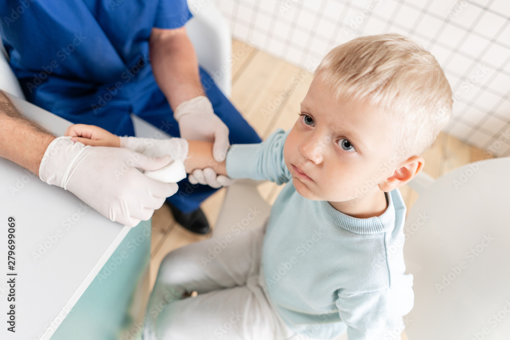 Doctor in blue uniform make elastic bandaged around a boy hand with trauma in his arm. in the hospital Doctor in blue uniform make elastic bandaged around a boy hand with trauma in his arm. in the hospital