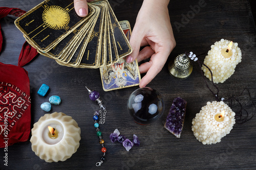 Fortune teller female hands and tarot cards on dark wooden table. Divination concept.