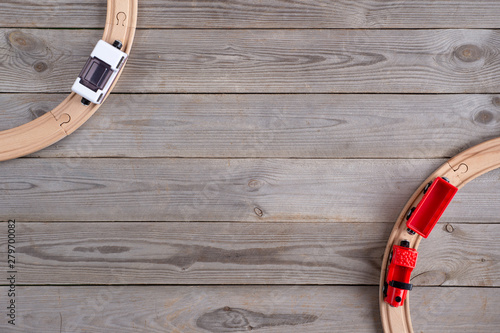 Toy train and wooden rails on wooden background. Top view. Copy space