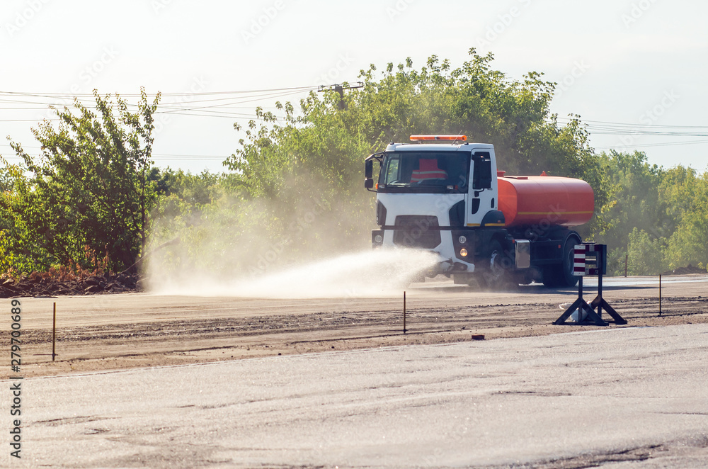 Truck watering the road with water. Irrigation of the road from dust, environmental protection