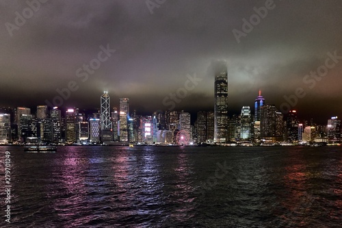 Hong Kong, Victoria harbour - skyline with skyscrapers in the night, cloudy sky