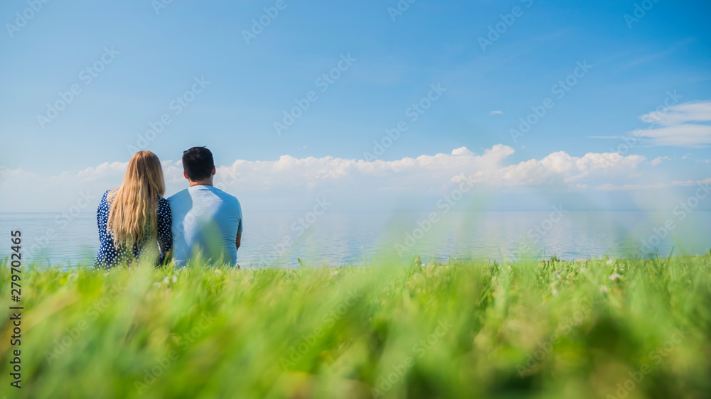 Multi-ethnic couple resting on the green grass, admiring the beautiful nature Multi-ethnic couple resting on the green grass, admiring the beautiful nature