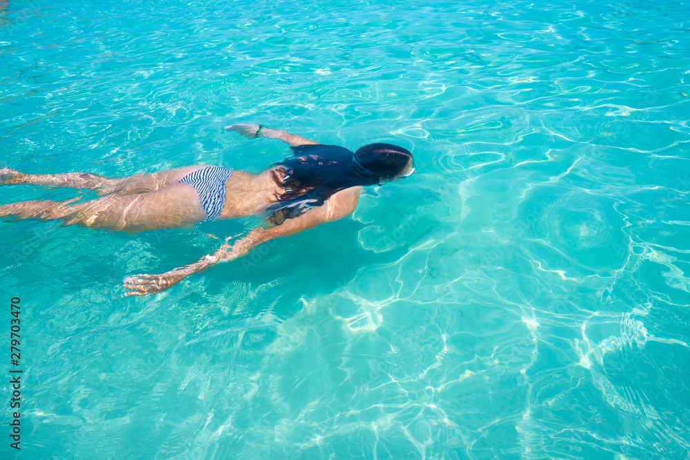Bikini girl swimming in clear Ibiza beach