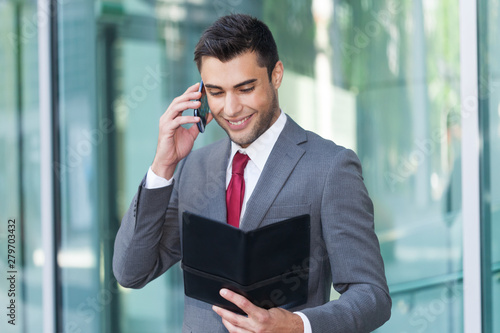 Businessman talking on the phone while reading notes photo