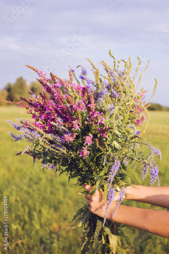 Fototapeta Naklejka Na Ścianę i Meble -  A huge bouquet of fragrant wildflowers in the hands of a girl