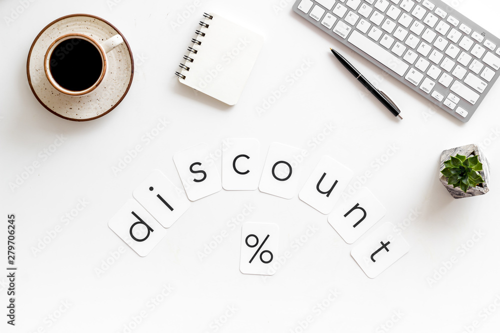 Office desk with notebook, discount word and percent sign on white background top view Office desk with notebook, discount word and percent sign on white background top view