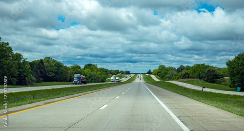 Long highway in the american countryside, blue cloudy sky background