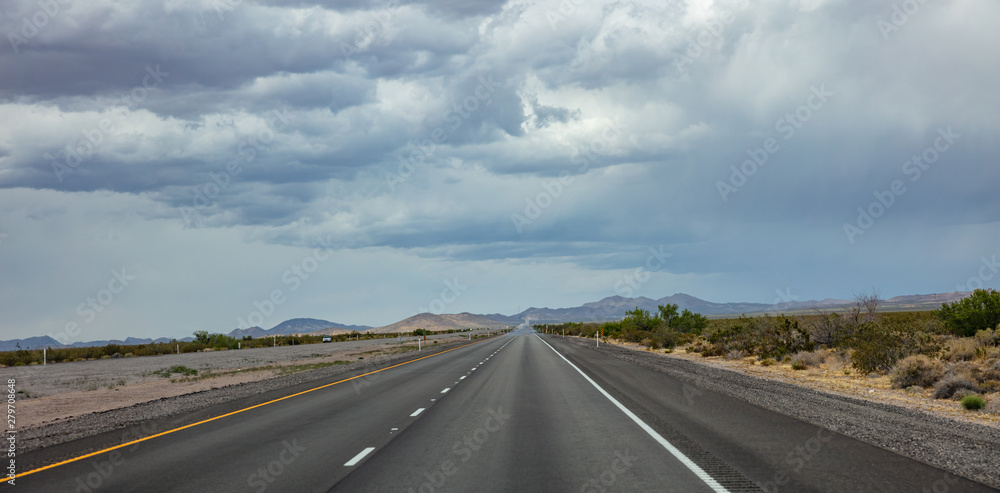 Long highway in the american desert, cloudy blue sky