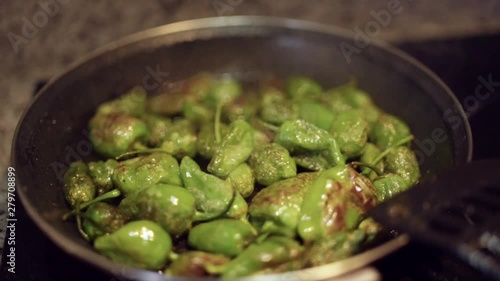 Frying and cooking Pimientos del Padron in a pan for spanish merienda tapas dinner in spain with dlicious food