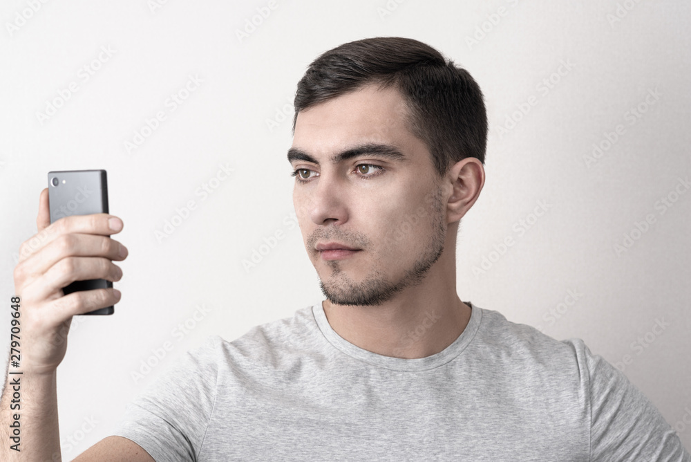 Caucasian man in t-shirt and smartphone in hand uses face recognition Caucasian man in t-shirt and smartphone in hand uses face recognition