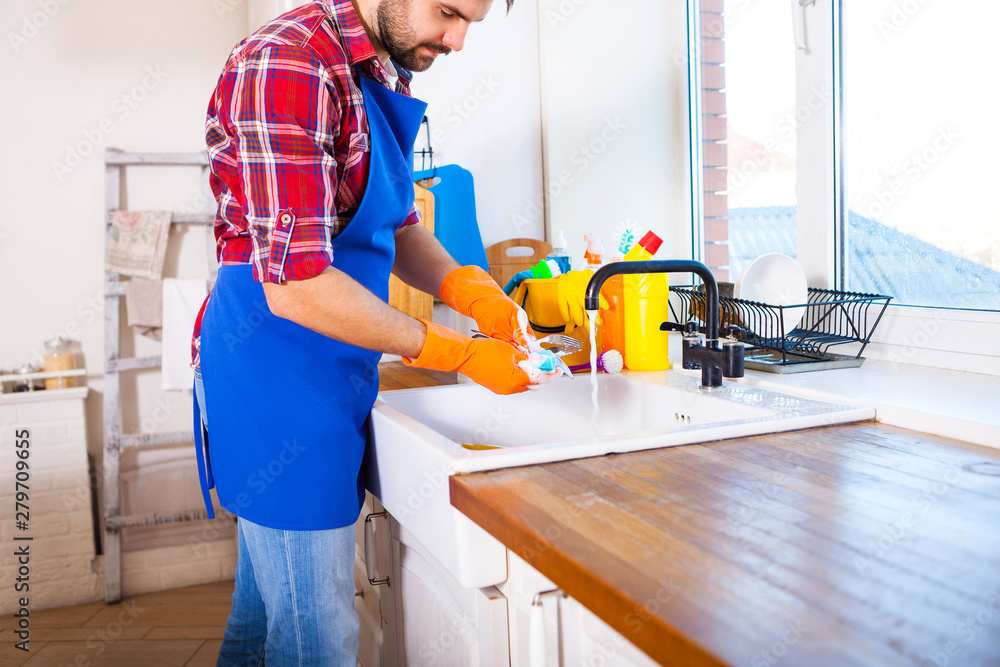 Man makes cleaning the kitchen. Young man washes the dishes. Cleaning concept. Man makes cleaning the kitchen. Young man washes the dishes. Cleaning concept.