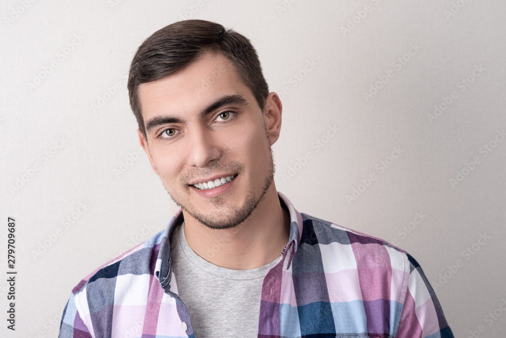 Authentic portrait of caucasian man in checkered pink shirt with perfect white smile on grey background Authentic portrait of caucasian man in checkered pink shirt with perfect white smile on grey background