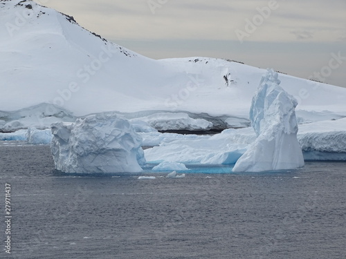 Iceberg flotando en el mar frente a una montaña de hielo en la antártica
