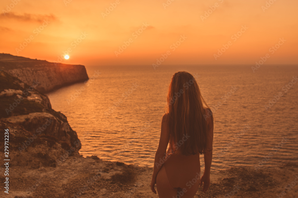 Young woman  staying on mountain on shore in body in sunset