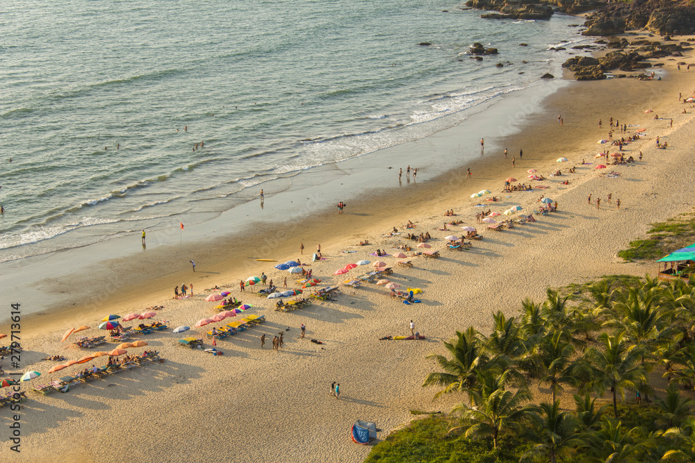 Arambol, Goa/India - 04.01.2019: people relax in beach beds with umbrellas and bathe in the sea, aerial view
