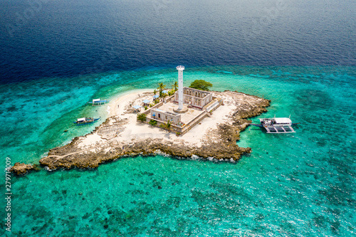 Aerial view of a tiny tropical island with a lighthouse surrounded by a huge coral reef (Capitancillo Island, Philippines) photo