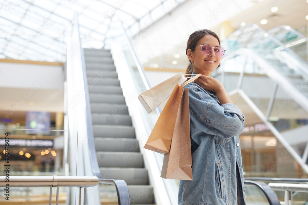 Young attractive smiling girl having fun in new glass mall while going shopping at weekend Young attractive smiling girl having fun in new glass mall while going shopping at weekend