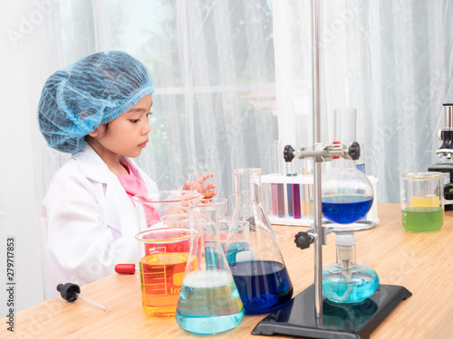 Little asian cute girl 6 years old role playing a scientist in science lab with equipment and chemicals. Learning and education of kid.