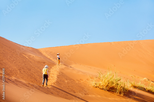 Kids climbing up red sand dune