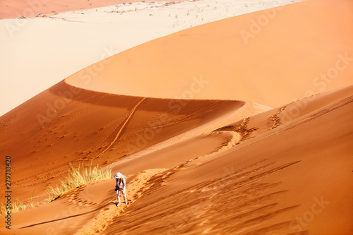 Young woman climbing up red sand dune