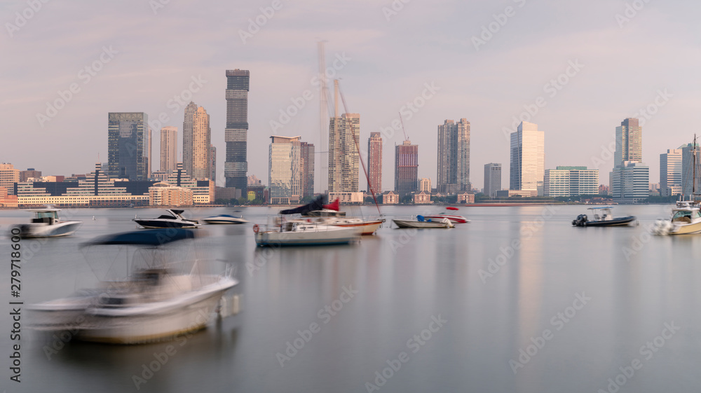 Jersey City skyscrapers from hudson river yacht club at sunrise with long exposure