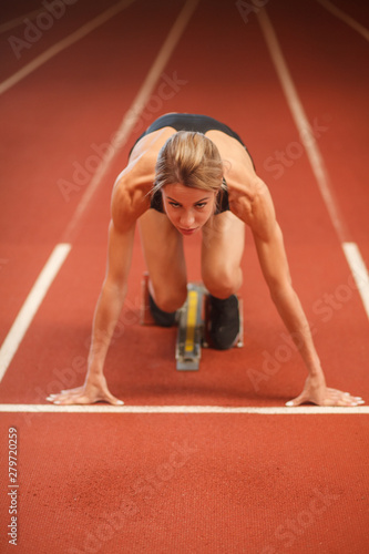 female jogger ready to start sprint on racetrack