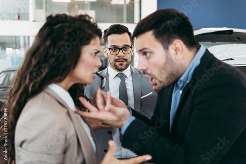 Angry married couple is discussing in a car sale salon or showroom © Dusko